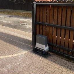 PHU SUN-TEL Cezary Dobrzyński - Drewniana brama wjazdowa z automatyką BFT w Pułtusku. Widoczny napęd bramy zamontowany przy słupku. Kostka brukowa na podjeździe.