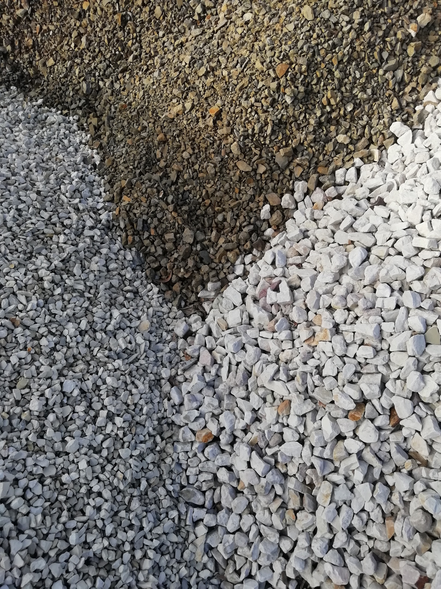 Trzy rodzaje kruszywa: białe, szare i brązowe, ułożone obok siebie w Grodzisku Mazowieckim.