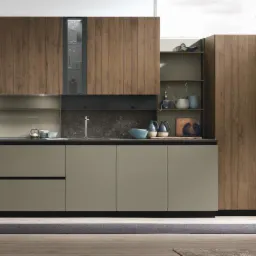 Nowoczesna kuchnia z frontami w odcieniach beżu i drewna, uzupełniona o blat z ciemnego kamienia i oświetlenie podszafkowe, z widocznym stołem barowym i krzesłami w tle.