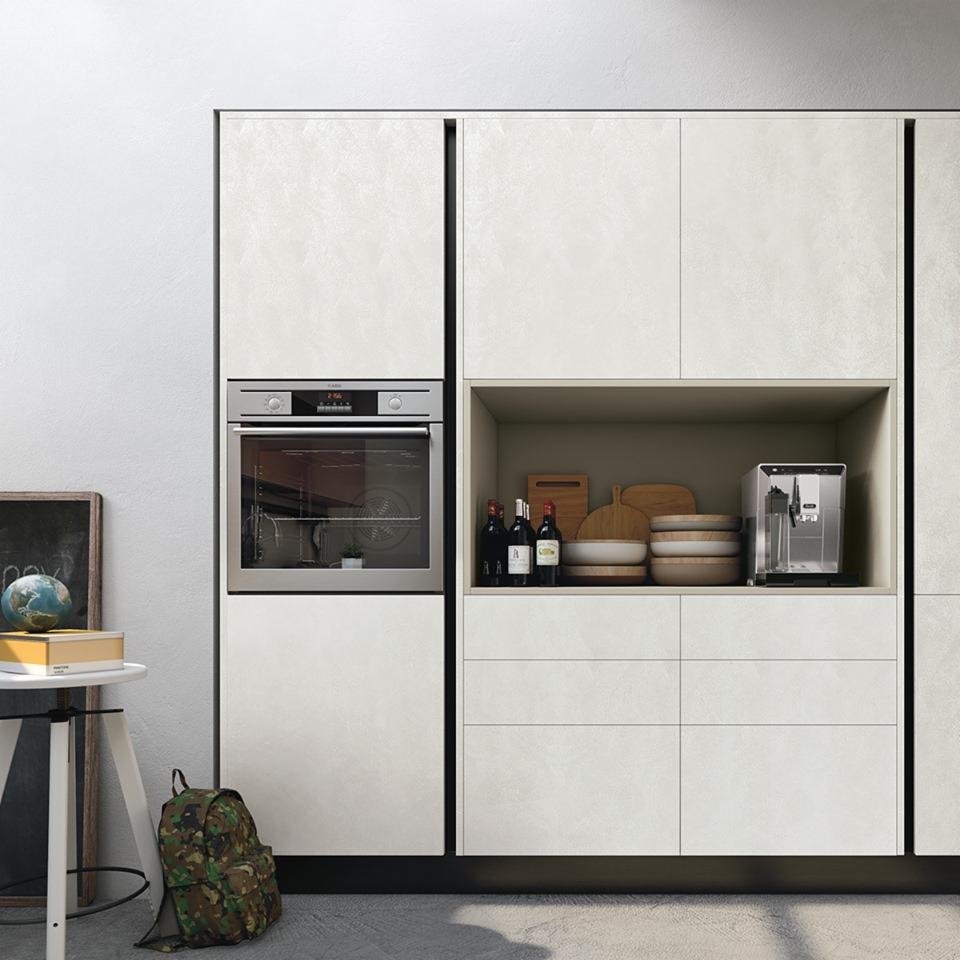 Kremowa zabudowa kuchenna z piekarnikiem i otwartą półką z akcesoriami, plecak moro przy blacie.