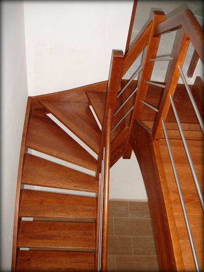 Drewniane schody spiralne z metalowymi poręczami, widok z góry na dół, jasne wnętrze.