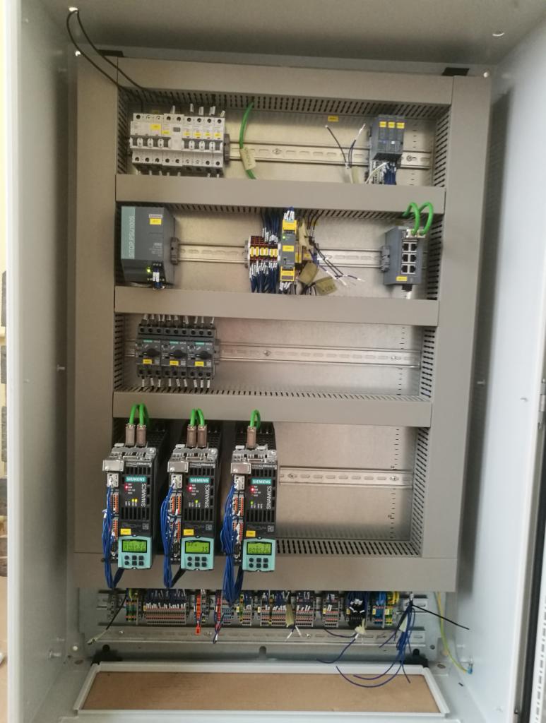 Wnętrze szafy sterowniczej z zainstalowanymi modułami Siemens Sinamics, bezpiecznikami i okablowaniem, widok z góry na dół.