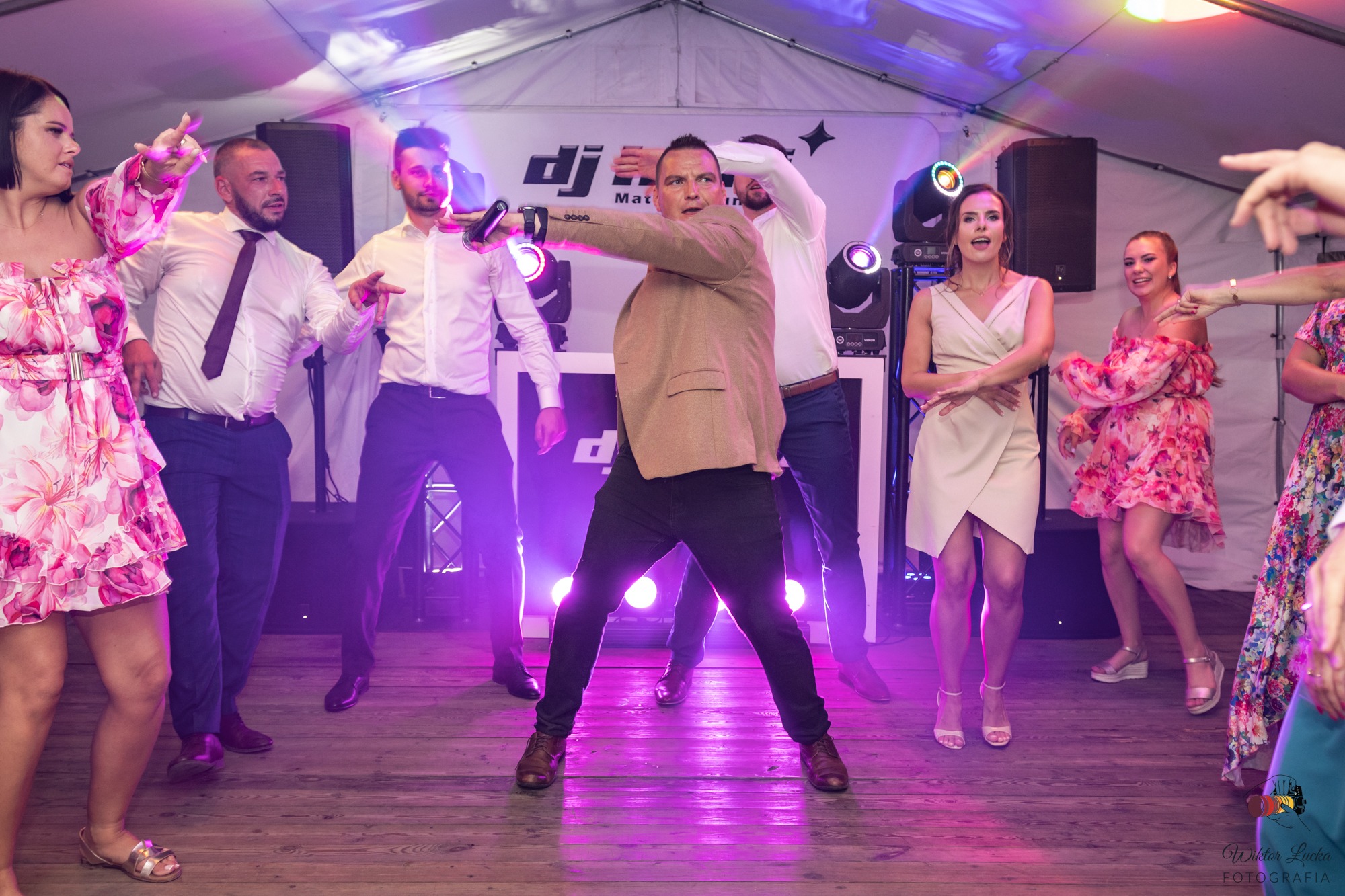 Zespół muzyczny prowadzi zabawę taneczną na weselu, oświetlenie sceniczne, drewniany parkiet.