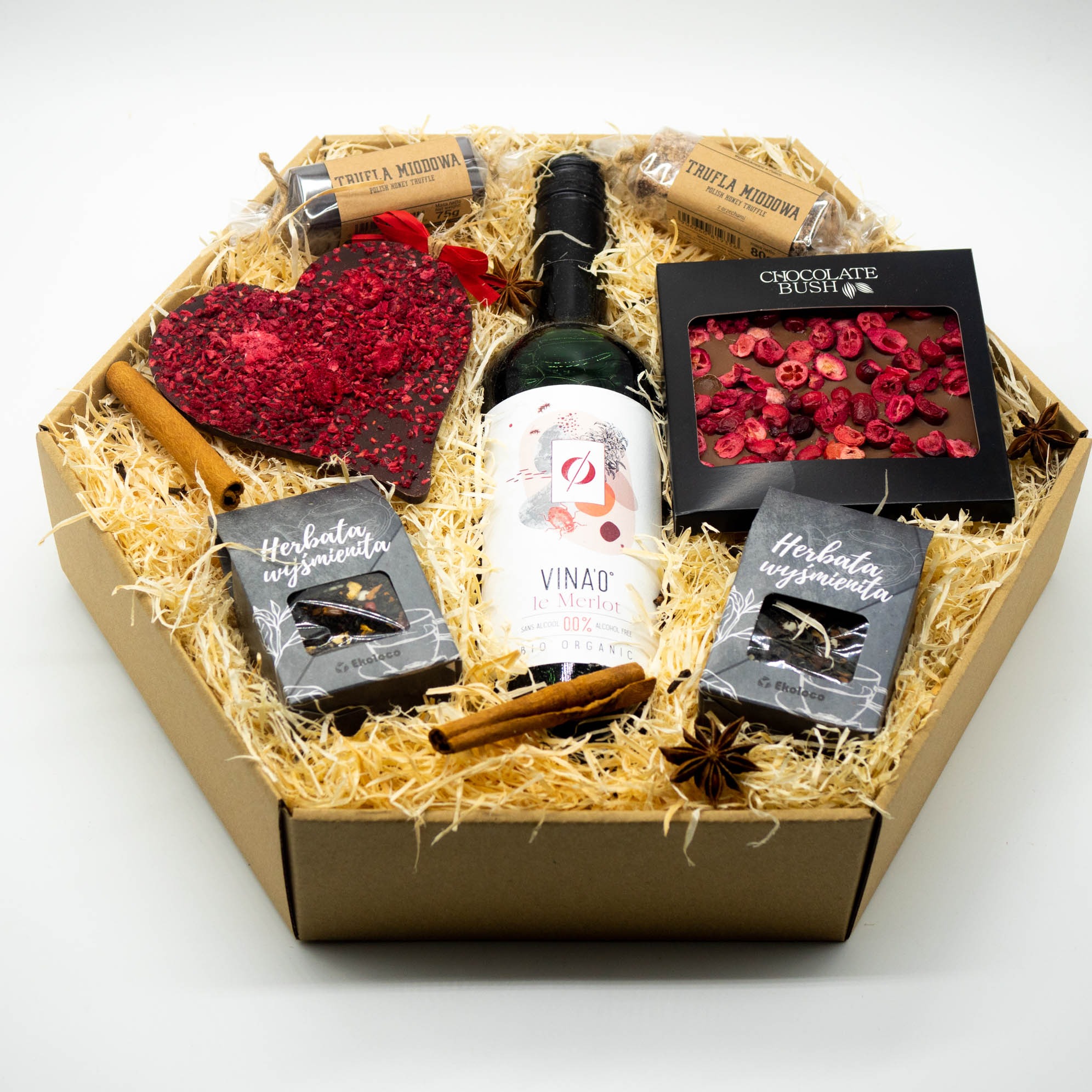 Elegancki kosz upominkowy: bezalkoholowe wino, herbaty, czekolada rzemieślnicza, przyprawy korzenne. Pudełko z naturalnym wypełnieniem, idealny prezent.