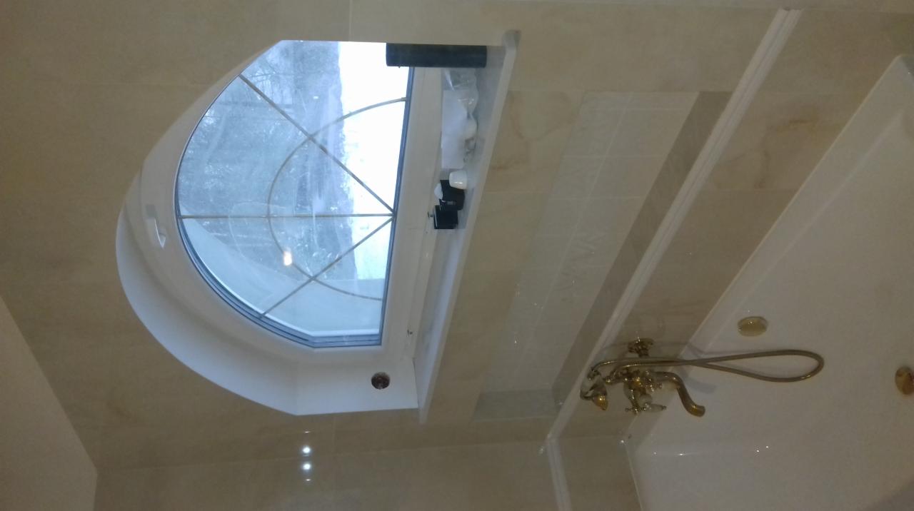 Beżowa łazienka z owalnym oknem w suficie, bateria wannowa w stylu retro z mosiądzu.