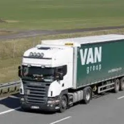 Ciągnik siodłowy Scania z naczepą VAN Group, widziany z boku na autostradzie, z widocznym znakiem drogowym w tle.