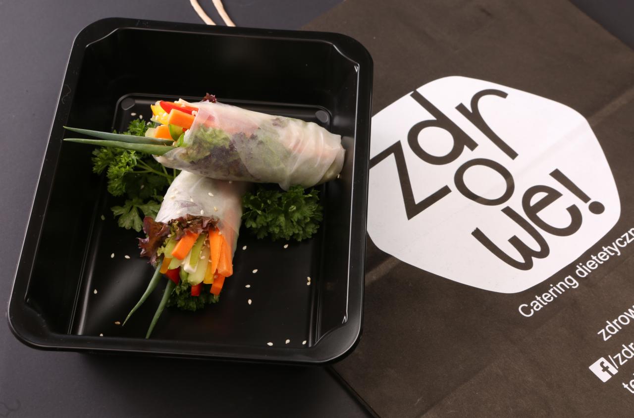 Dwa wiosenne sajgonki z warzywami w czarnym pudełku na wynos, z logiem firmy cateringowej z Miłek w tle.