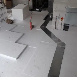 Montaż instalacji ogrzewania podłogowego w Łochowie, widoczne płyty styropianowe EPS układane na podłodze i kanał wentylacyjny ze stali nierdzewnej.