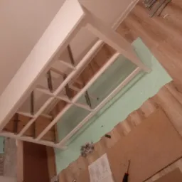 Montaż sufitu podwieszanego w Podleśnem. Widoczna konstrukcja z profili i płyt karton-gips, przygotowana do dalszych prac wykończeniowych. Narożnik ujęty z dołu.