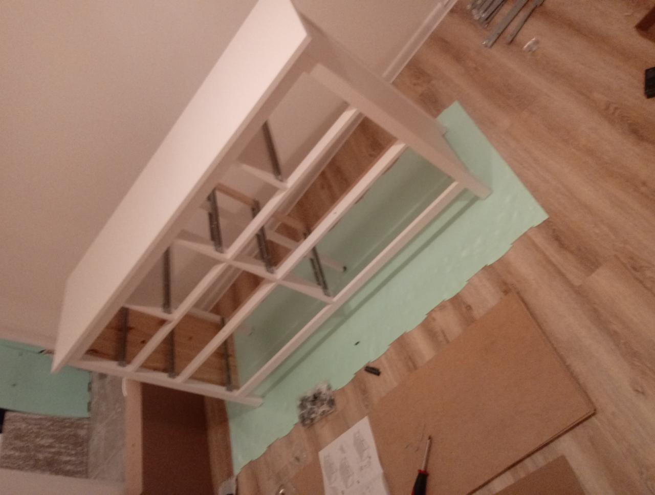 Montaż sufitu podwieszanego w Podleśnem. Widoczna konstrukcja z profili i płyt karton-gips, przygotowana do dalszych prac wykończeniowych. Narożnik ujęty z dołu.