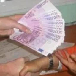 Przekazywanie pliku 500 euro między dwiema osobami; widoczne dłonie, banknoty i fragmenty dokumentów na stole.