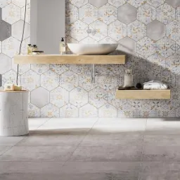 Nowoczesna łazienka z heksagonalnymi płytkami na ścianie w odcieniach szarości, błękitu i złota, betonowa ściana z lewej strony i szare płytki podłogowe.