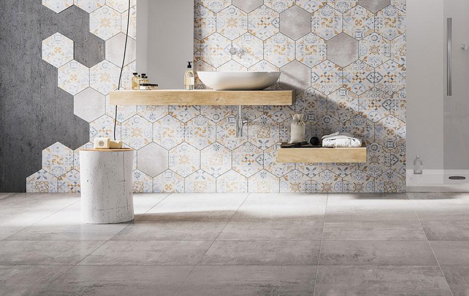 Nowoczesna łazienka z heksagonalnymi płytkami na ścianie w odcieniach szarości, błękitu i złota, betonowa ściana z lewej strony i szare płytki podłogowe.