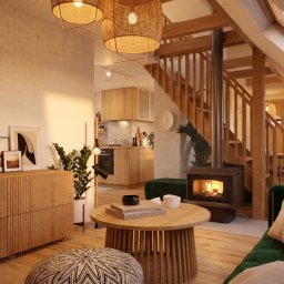 martarudnicka.art - Jasne wnętrze domu ze schodami i kominkiem. Drewniane meble, lampy z abażurami z wikliny, zielona sofa i rośliny doniczkowe tworzą przytulną atmosferę.