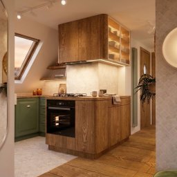 martarudnicka.art - Klimatyczna kuchnia w skandynawskim stylu z drewnianą wyspą, zielonymi szafkami i oknem dachowym. Widok przez lustro na schody i pufę.