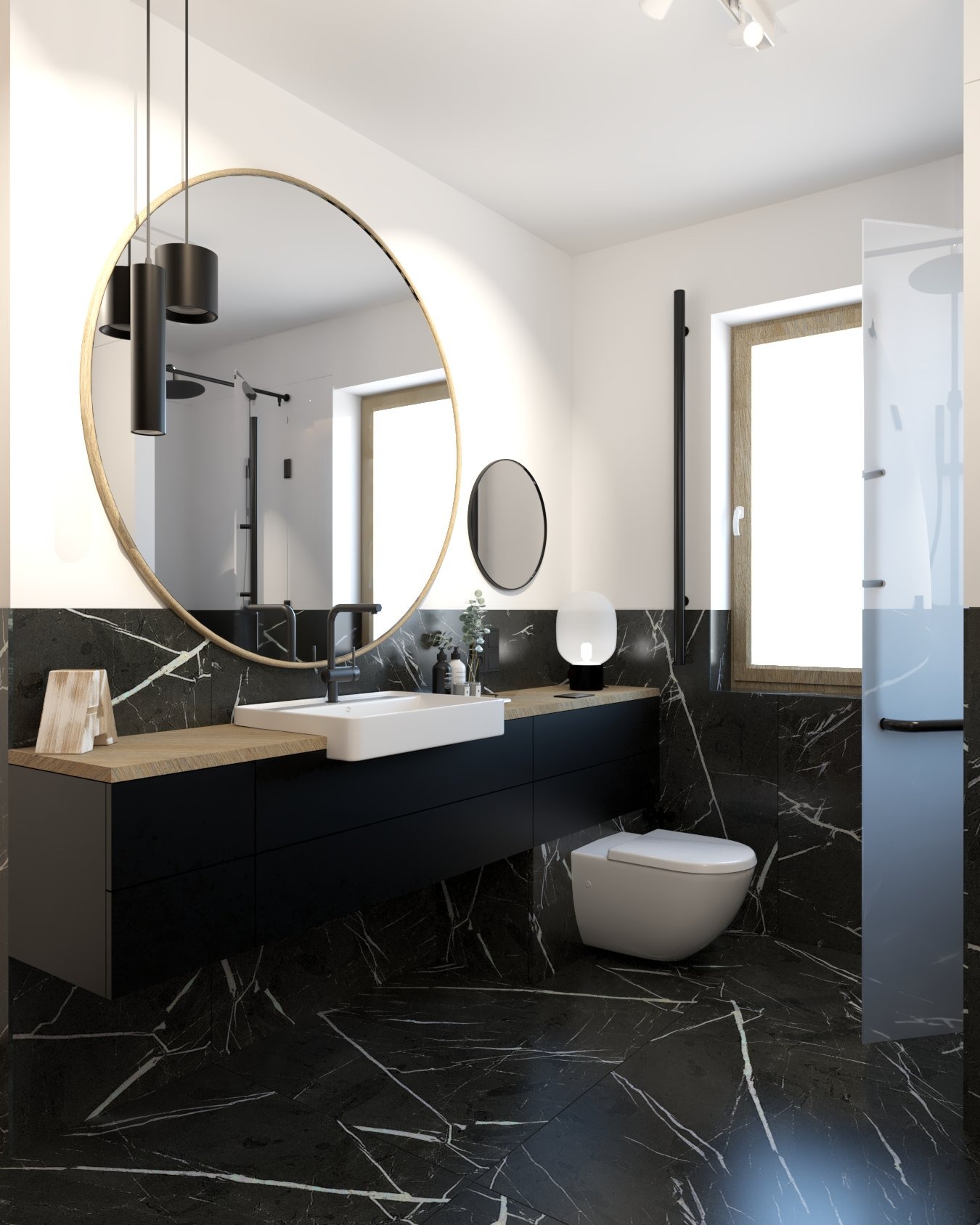 Nowoczesna łazienka z czarnymi marmurowymi płytkami, okrągłym lustrem w złotej ramie i wiszącą toaletą.