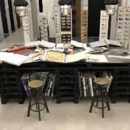 Ekspozycja w salonie: stół z palet z katalogami i próbkami klamek, uchwytów i wykończeń.