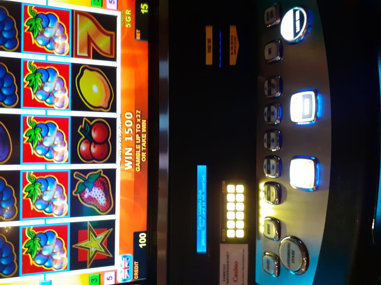 Automat do gier z wygraną 1500, widoczne owoce na bębnach i przyciski sterujące, informacja o braku włożonej karty lojalnościowej.