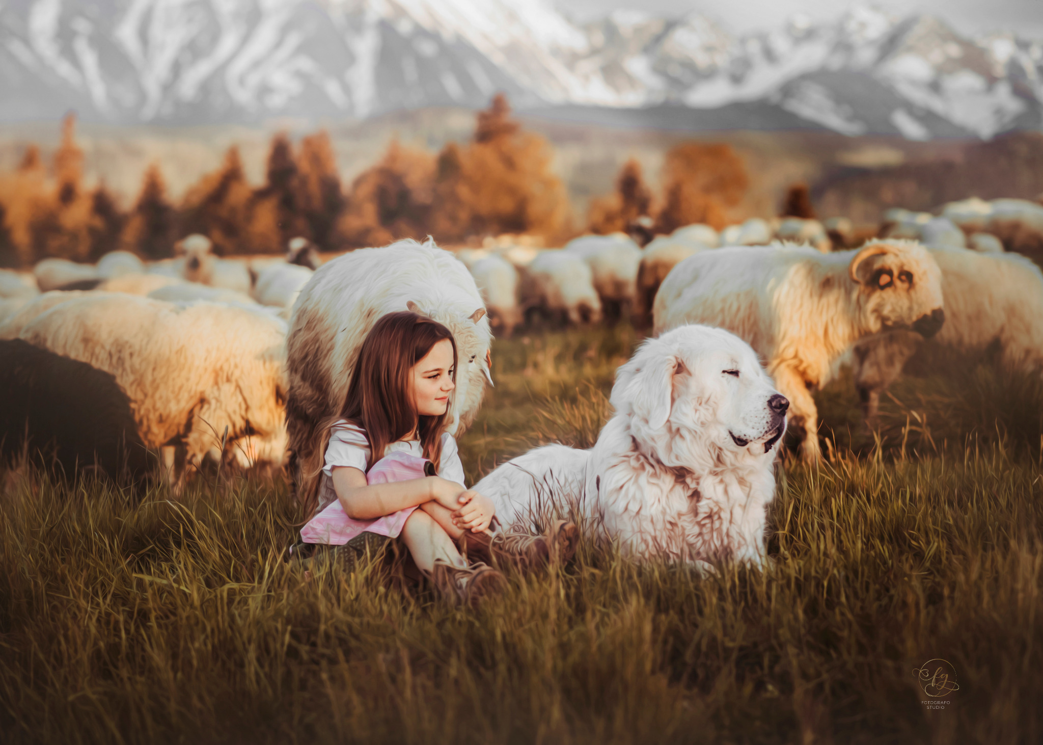 Dziewczynka siedzi na trawie obok owczarka podhalańskiego, w tle stado owiec i górski krajobraz o zachodzie słońca.