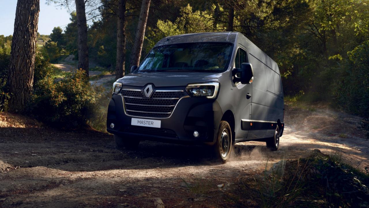 Nowoczesny, grafitowy bus Renault Master na leśnej, szutrowej drodze, z widocznym logo i nazwą modelu na przedniej masce.