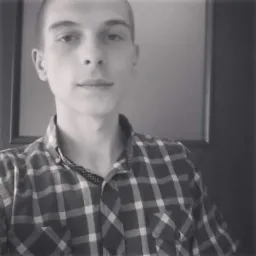 Czarno-białe selfie mężczyzny w koszuli w kratę na tle drzwi.