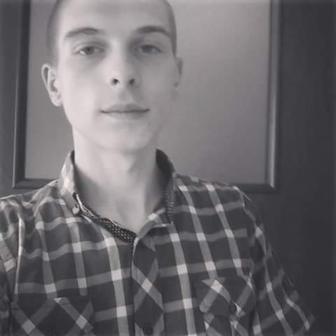 Czarno-białe selfie mężczyzny w koszuli w kratę na tle drzwi.