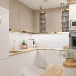 Jasna, minimalistyczna kuchnia z białymi frontami, złotymi akcentami i drewnianym blatem, wyposażona w sprzęt AGD w zabudowie i dekoracje roślinne.