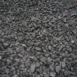 Kupa węgla orzech o nieregularnych kształtach, lekko wilgotna, z widocznymi refleksami światła na powierzchni.