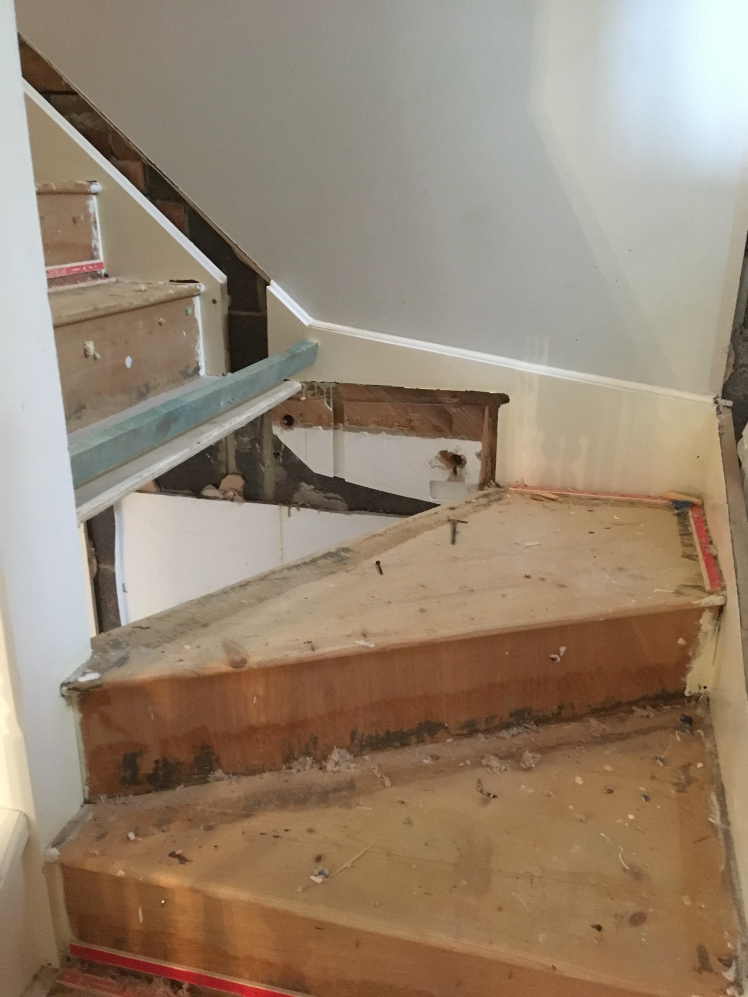 Schody w trakcie remontu: widoczne drewniane stopnie, częściowo zdemontowane elementy konstrukcyjne, ślady prac wykończeniowych na ścianach.