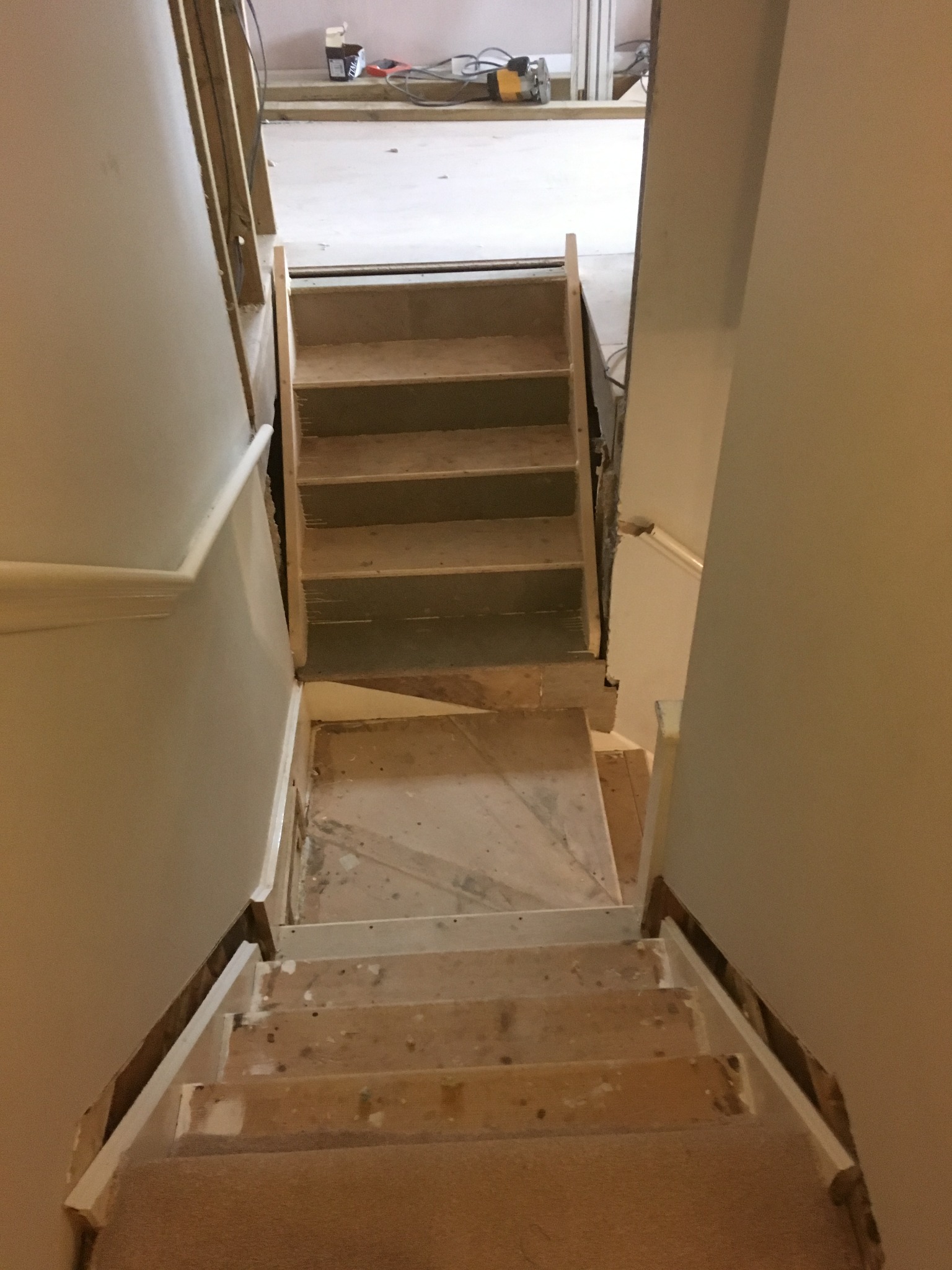 Widok z góry na schody w trakcie remontu, z widocznymi surowymi stopniami i przygotowanymi do malowania ścianami.