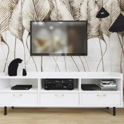 Biała szafka RTV z czarnymi figurkami kotów na tle tapety w złote liście i wiszącego telewizora, oświetlona dwoma czarnymi lampami