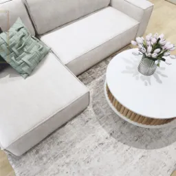 Beżowa sofa narożna z poduszkami w odcieniach szarości i zieleni, okrągły stolik kawowy z białym blatem i drewnianą podstawą, bukiet tulipanów w szklanym wazonie, dywan w odcieniach szarości...