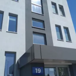 Fasada nowoczesnego budynku biurowego z numerem 19, widok z dołu w słoneczny dzień.