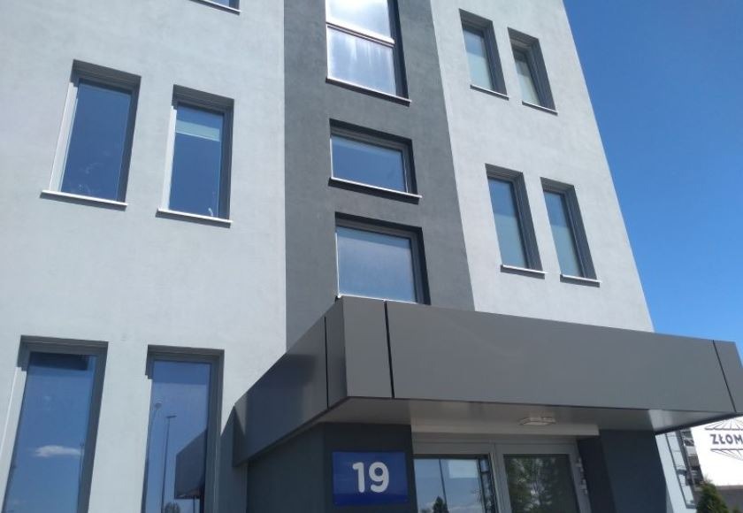 Fasada nowoczesnego budynku biurowego z numerem 19, widok z dołu w słoneczny dzień.