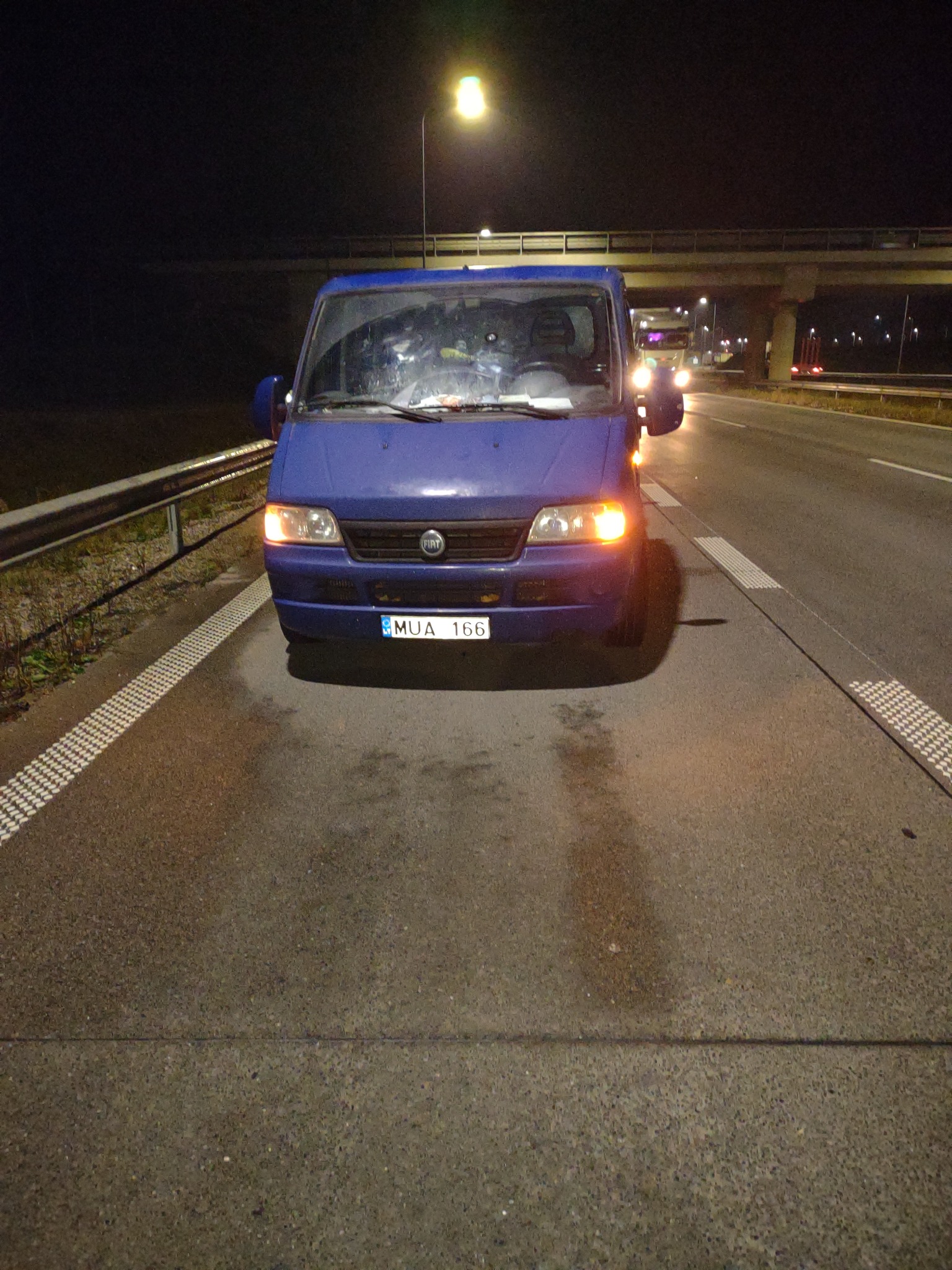 Niebieski bus Fiat Ducato na poboczu autostrady w nocy, światła włączone, widoczny numer rejestracyjny MUA 166.