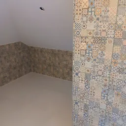 Ukończona łazienka na poddaszu z wzorzystymi płytkami na ścianach i podłodze. Płytki w odcieniach beżu, brązu i niebieskiego tworzą unikalny, dekoracyjny efekt.