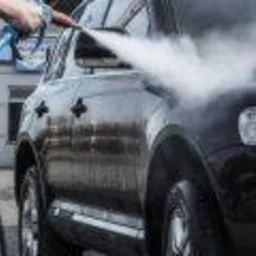 Czarny samochód SUV spryskiwany wodą pod ciśnieniem z niebieskiego pistoletu natryskowego, widoczna para wodna i odbicia na lakierze.