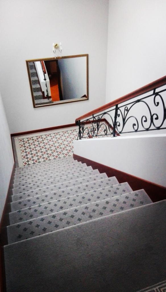 Wykładzina dywanowa na schodach z wzorem w drobne krzyżyki, widok z góry, z lustrem na ścianie odbijającym fragment schodów
