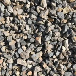 Drobne kamienie o nieregularnych kształtach w odcieniach szarości i beżu, wypełniające całą klatkę kadru, bez widocznych elementów otoczenia.