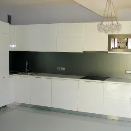 Nowoczesna, minimalistyczna kuchnia z białymi, lakierowanymi frontami szafek, szarym panelem nad blatem, designerską lampą wiszącą i wbudowanymi sprzętami AGD.