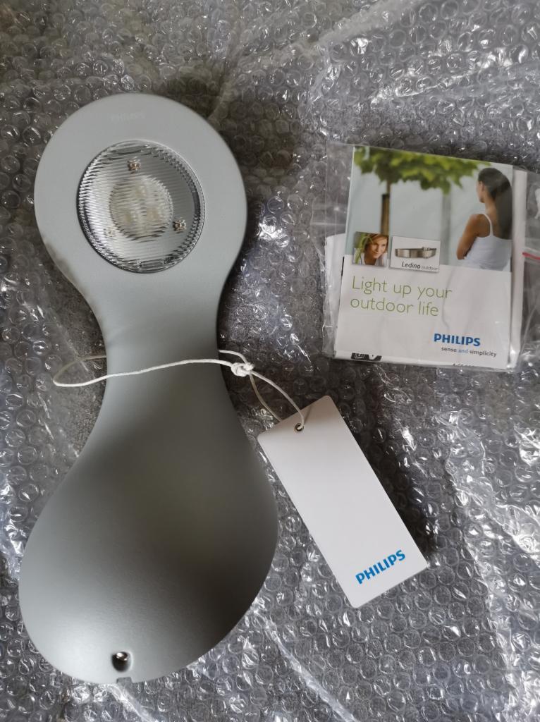Szara lampa LED Philips do oświetlenia zewnętrznego, z etykietą i ulotką informacyjną na folii bąbelkowej.