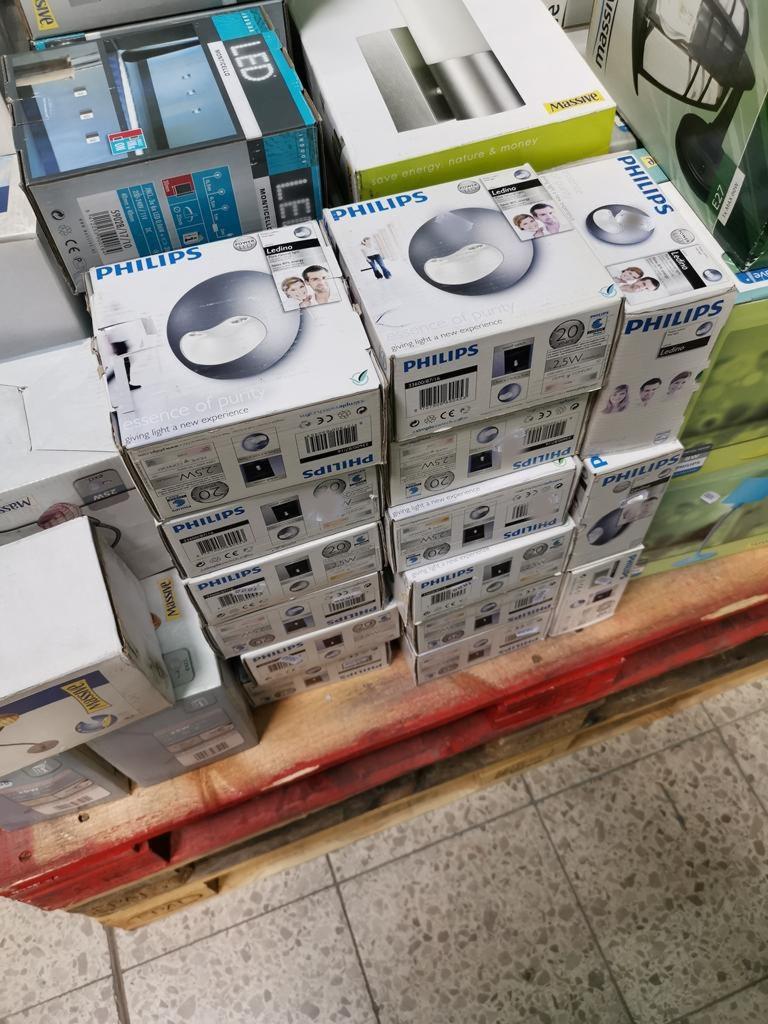 Stos opakowanych lamp sufitowych Philips Ledino na palecie w magazynie, widoczne etykiety z informacjami o produkcie.