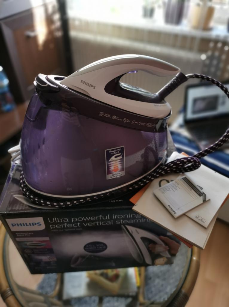 Żelazko parowe Philips PerfectCare Aqua Pro na pudełku, z widocznymi instrukcjami i przewodem zasilającym w czarno-białą kratkę.