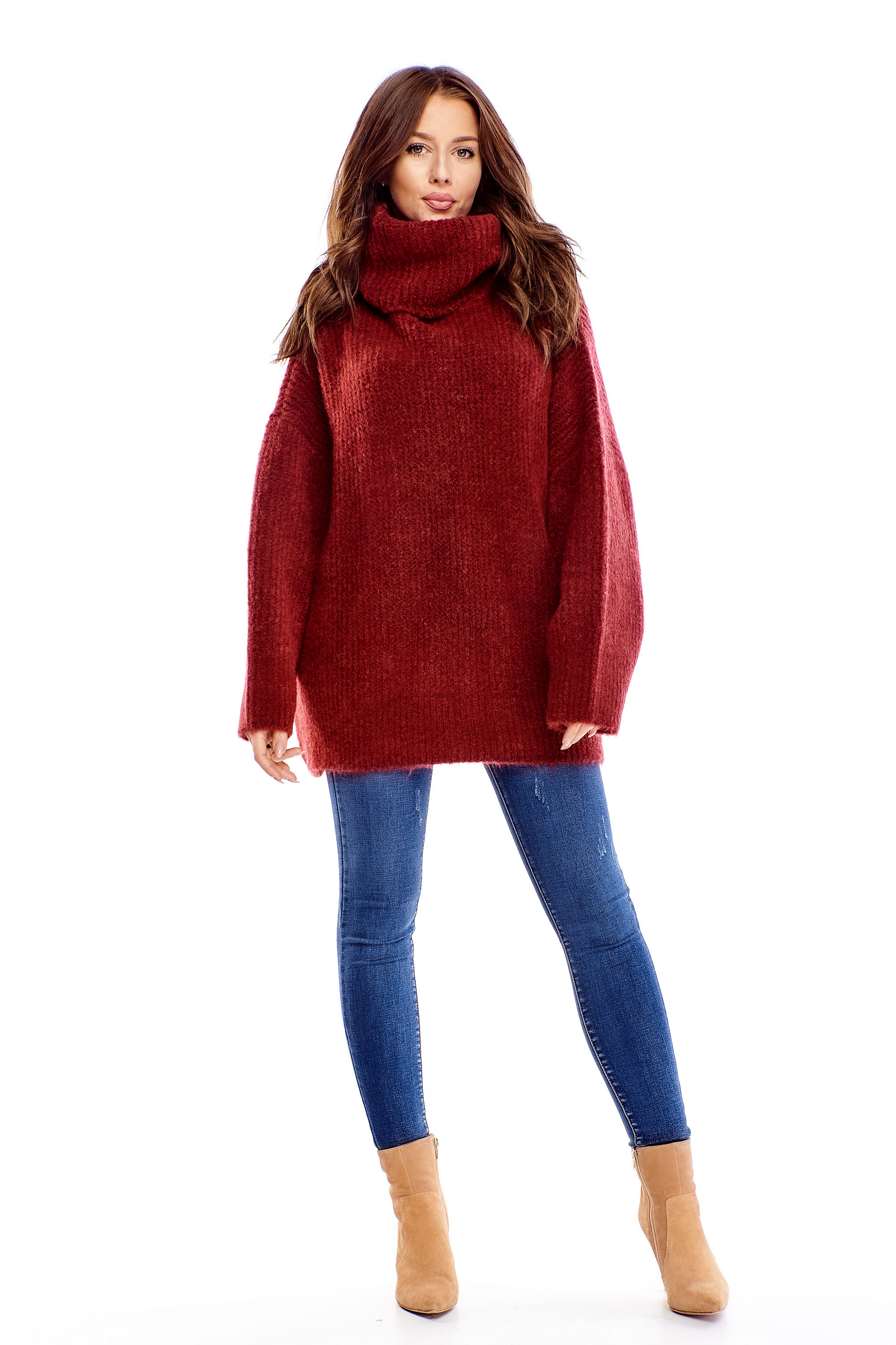 Modelka w bordowym, wełnianym swetrze z golfem, dżinsach i zamszowych botkach na białym tle.