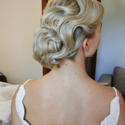 HD Make Up Hanna Durczak - Elegancka upięta fryzura blond z tyłu głowy kobiety w sukni ślubnej, widoczny tatuaż na karku i fragment pokoju.