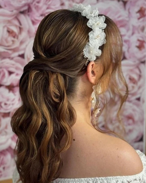 Elegancka fryzura ślubna upięta z boku, z kwiatową opaską i kolczykami, wykonana przez fryzjera w Kościanie. Brązowe włosy z refleksami.