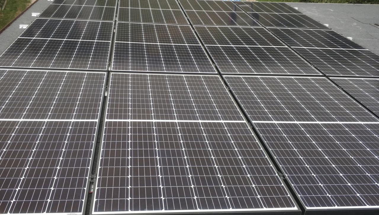 Instalacja paneli fotowoltaicznych na płaskim dachu w Warszawie, widok z góry ukazuje pełną strukturę modułów.