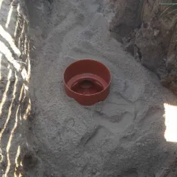 Wykonany wykop z piaskowym podsypem i wstawionym elementem betonowego szamba w trakcie montażu.