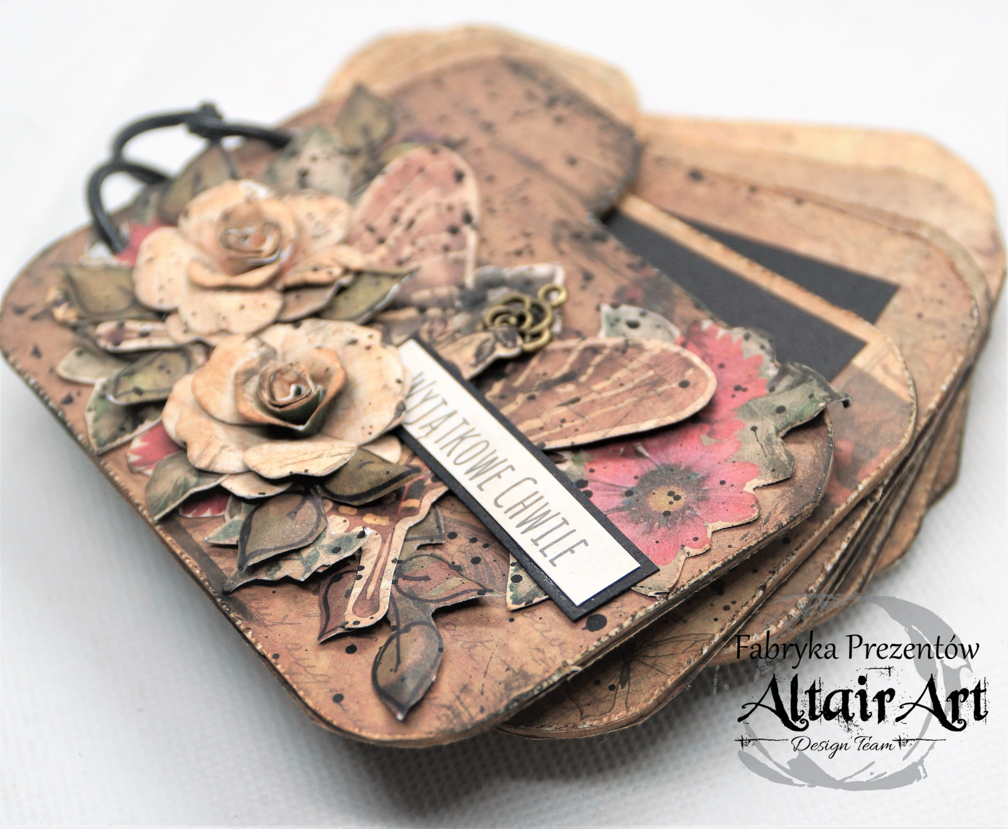 Ręcznie robiony album na zdjęcia w stylu vintage, zdobiony papierowymi kwiatami i napisem 'Wyjątkowe Chwile', z widocznym logo 'Fabryka Prezentów Altair Art'.