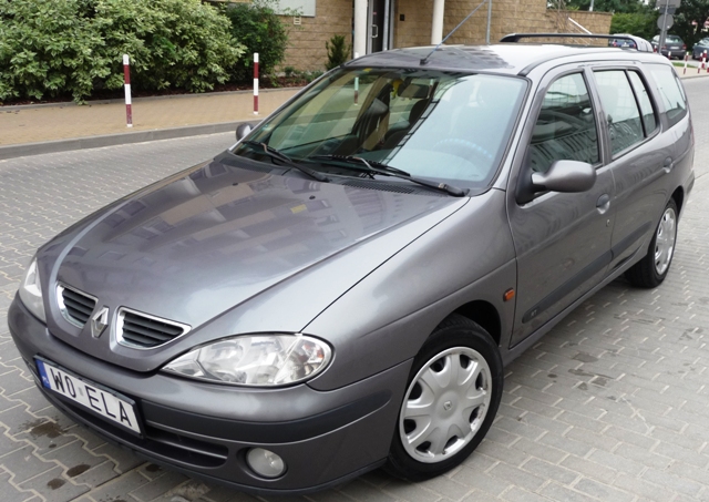 Szary samochód Renault Megane kombi z 2000 roku, zaparkowany na chodniku z kostki brukowej, widok z przodu i z boku.